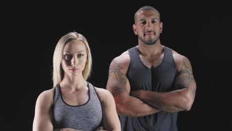 Portrait-shot-of-an-athletic-man-and-woman-with-their-arms-crossed-on-a-dark-background