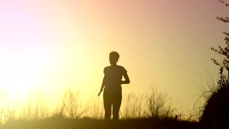 Junge-sportliche-Frau-läuft-im-Freien-bei-Sonnenuntergang-in-Berglandschaft.