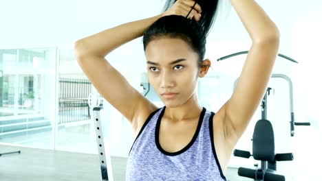 Young-asian-woman-making-ponytail-in-the-fitness-gym.-Woman-exercise-at-fitness-gym.-Sport-and-Reaction-concept.-4k-Resolution.