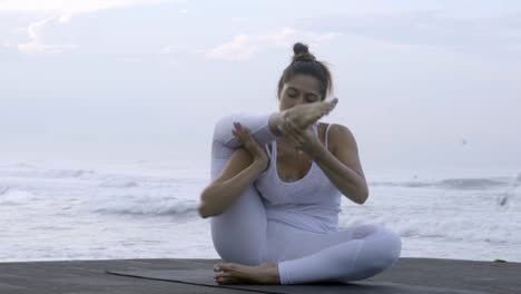 Reife-Frau-praktizieren-Yoga-an-Küste