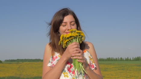 Porträt-der-Frau-im-Feld-mit-Blumenstrauß-gelbe-Löwenzahn-ihn-schnüffeln