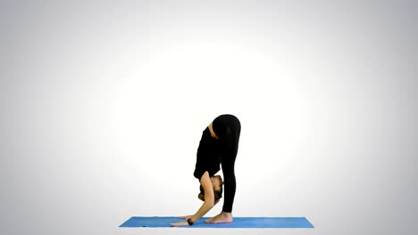 Young-woman-doing-yogic-sun-salutation-pose-on-mat-on-white-background