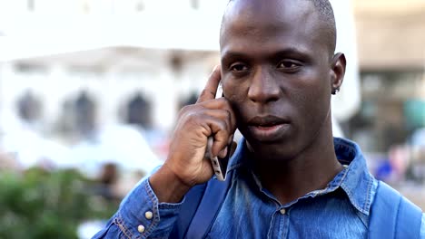 handsome-black-african-man-talking-by-phone-in-the-street--close-up