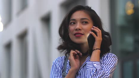 Mujer-asiática-joven-usando-el-teléfono-inteligente-en-la-calle