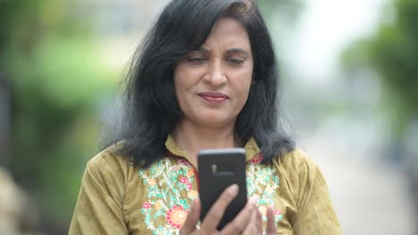 Mature-beautiful-Indian-woman-using-phone-in-the-streets-outdoors