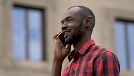 Smiling-happy-young-black-man-in-the-street,-talking-by-phone