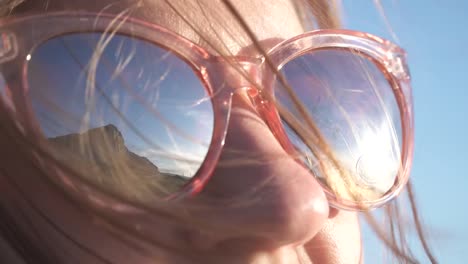 Sky-and-mountains-are-reflected-in-the-glasses-of-a-young-girl