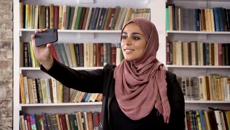 Joven-musulmanes-mujeres-bellas-hijab-tomar-selfie-luego-mirando-en-el-teléfono-y-viendo-fotos-en-la-biblioteca,-sonriendo