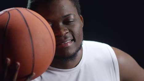 Jugador-de-baloncesto-negro-posando-sobre-fondo-oscuro