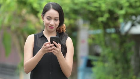 Junge-schöne-asiatische-geschäftsfrau-mit-Telefon-in-den-Straßen-im-freien