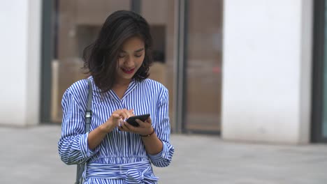 Usar-el-teléfono-en-la-ciudad,-4k-por-una-mujer-bonita