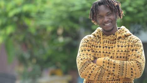 Young-happy-handsome-African-man-smiling-with-arms-crossed-in-the-streets-outdoors