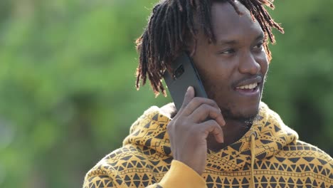 Young-happy-handsome-African-man-smiling-while-calling-in-the-streets-outdoors