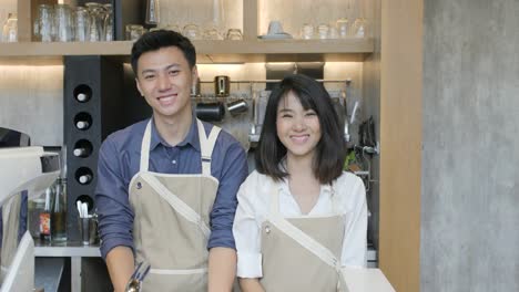 Porträt-von-zwei-asiatischen-Barista-mit-Tablet-auf-den-Arbeitstag-im-Coffee-Shop-und-lächelnd-vor-der-Kamera