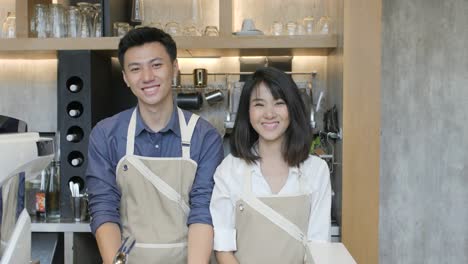 Portrait-of-two-asian-barista-using-tablet-at-the-work-day-in-the-coffee-shop-and-smiling-on-camera