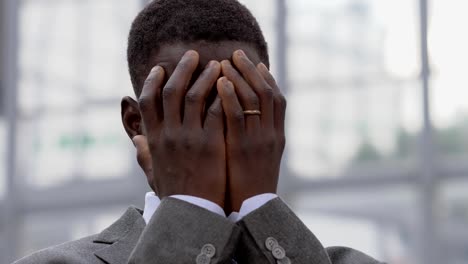 verzweifelten-schwarzen-afrikanischen-Geschäftsmann-legte-seine-Hände-auf-Gesicht---im-freien