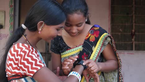 Two-friends-with-a-smart-watch-latest-using-it-figuring-out-working-touchscreen-enjoying-laughing-close-up-two-shot-looking-at-camera-taking-instructions-thrilled-beautiful-lovely-and-lively-laugh