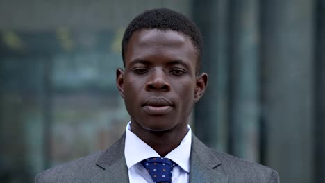 Ernsthafte-zuversichtlich-schwarzen-jungen-Geschäftsmann-starrte-auf-Kamera-outdoor