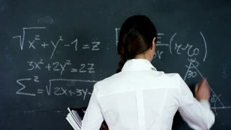 Portrait-of-a-beautiful-girl,-teacher-or-student-solves-examples,-formulas,-triangle-on-a-black-board,-on-a-black-background.