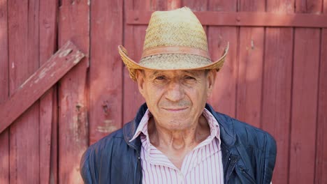 Portrait-of-an-elderly-farmer-in-a-straw-hat-on-a-farm-background.-Face-of-a-man-in-age