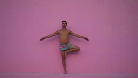 Mixed-race-hispanic-young-man-with-naked-torso-practicing-yoga-fitness-exercise-on-pink-background.-Sport,-meditation-and-lifestyle-concept.-Peaceful-Meditation-for-good-health