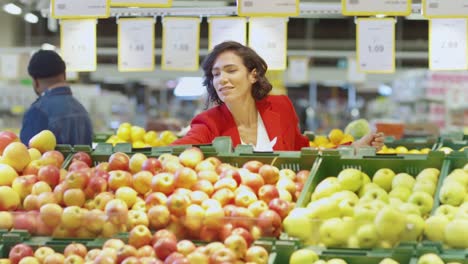 En-el-supermercado:-hermosa-mujer-Elige-frutas-orgánicas-en-el-fresco-producen-sección-del-mercado-del-agricultor.-Les-recoge-frutas-y-lugares-en-su-cesta-de-la-compra.-Cámara-lenta.