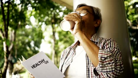 Asian-senior-man-reading-Healthy-Life-book-alone-in-the-park