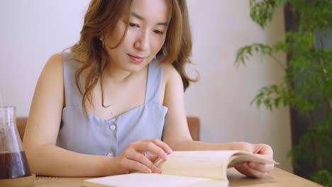 Junge-chinesische-Studentin-mit-Büchern-In-der-Bibliothek