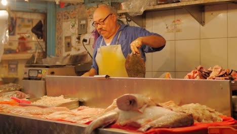 Un-hombre-ayuda-a-sus-clientes-mientras-trabajaba-en-un-mercado-de-pescado-en-México