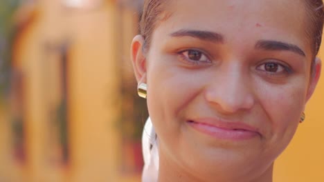 A-beautiful-hispanic-woman-looks-into-the-camera-against-an-orange-wall-in-Mexico