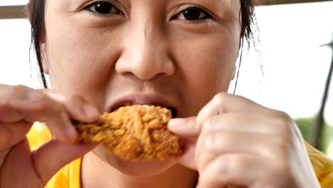 Close-up-Cute-asian-woman-are-happy-eating-fried-chicken-leg-in-restaurant.-Video-4k-Slow-motion