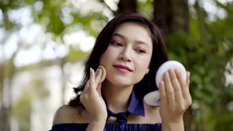 woman-applying-make-up-with-powder-puff