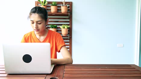 Frau-mit-Laptop-in-Balkon-im-Freien.-Junge-Frau-mit-Laptop-auf-Holztisch-Balkon-sitzt.-Digital-Nomad-Konzept.