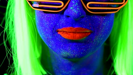 Woman-with-UV-face-paint,-wig,-UV-glasses,-glowing-clothing-portrait,-licking-lip,-face-close-up-of-make-up.-Caucasian-woman.-.