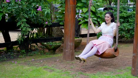 happy-young-woman-in-Thai-traditional-dress-relaxing-on-a-wooden-swing