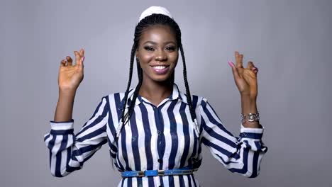 pretty-african-woman-crossing-her-fingers-for-luck-at-the-camera-on-gray-background