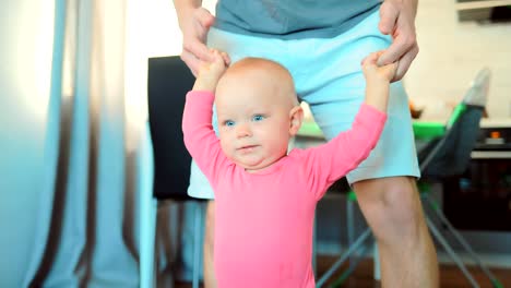 Child-holds-hands-with-his-father-and-takes-the-first-steps