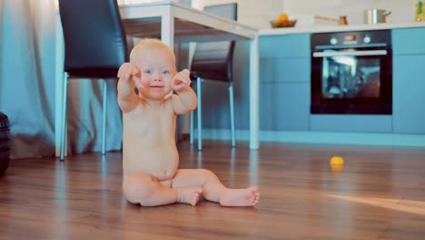 Poco-chica-rubia-desnuda-sentada-en-el-piso-en-un-apartamento-y-mirando-a-la-cámara