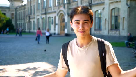 Awesome-surprised-asian-guy-is-showing-confused-gesture-with-emotional-face-while-standing-next-to-the-old-building-alone