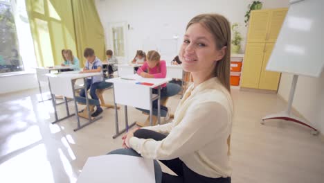Porträt-des-jungen-Erzieher-weiblich-im-Unterricht-mit-Schülern-im-Klassenzimmer-an-der-Junior-School-auf-unscharfen-Hintergrund