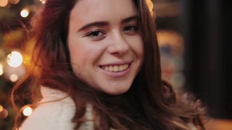 Girl-have-fun-near-Christmas-tree-and-smile-to-camera