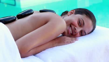 Peaceful-brunette-getting-hot-stone-massage-poolside