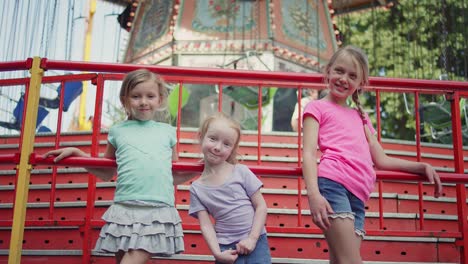 Tres-niñas-gire-alrededor-y-sonrisa-frente-de-un-paseo-en-carnival