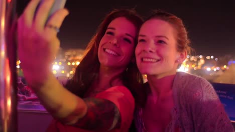 Zwei-Freunde,-die-selfies-auf-dem-Riesenrad-in-Nacht