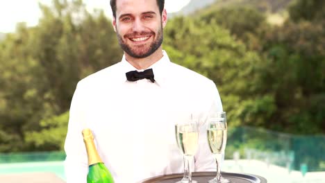 Smiling-waiter-holding-champagne-bottle-and-flute