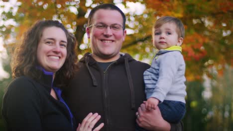 Family-of-three-posing-for-a-photo-in-front-of-a-tree