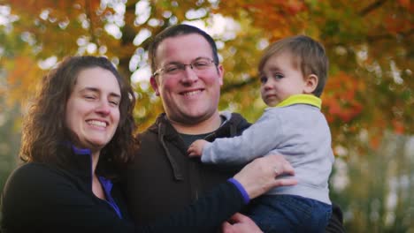 Family-posing-for-a-photo-in-front-of-tree,-baby-boy-not-looking-at-the-camera