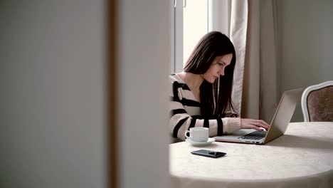 Frau-nutzt-Laptop-und-genießen-Sie-Kaffee-am-Morgen-auf-einen-hellen-Speisesaal.-Schieberegler-nach-rechts,-Blick-durch-die-offenen-Türen