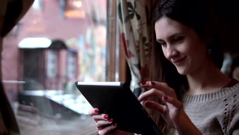 Beautiful-young-girl-using-tablet-computer-touchscreen-in-cafe