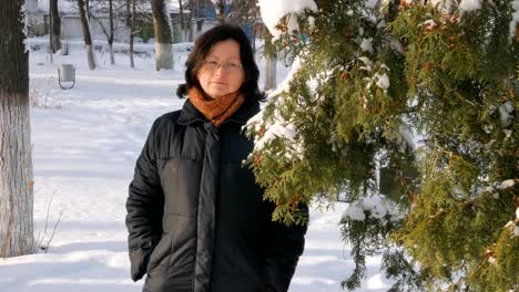 A-young-woman-in-a-Park-with-fir-on-the-street,-hands-touch-the-branches-of-trees,-examining-them.-Season-winter